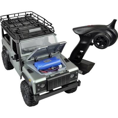 Spielzeug-Geländewagen mit offenem Motorhaube, zeigt eine blaue Batterie im Inneren. Neben dem Auto liegt eine schwarze Fernsteuerung.