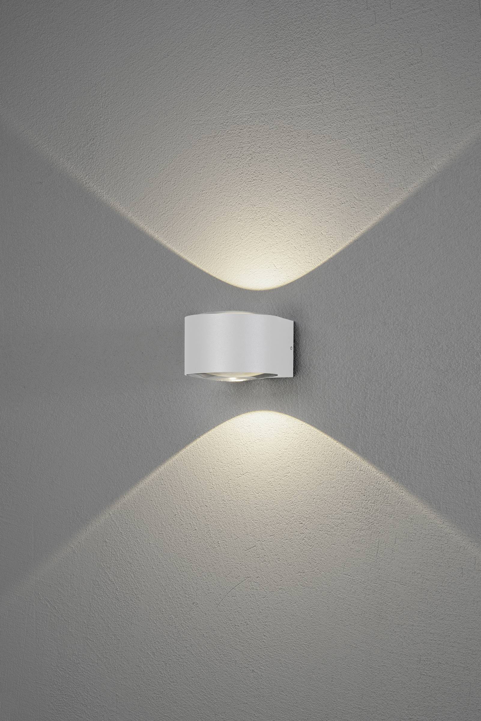 Wandleuchte mit modernem Design aus Metall, leuchtet nach oben und unten, erzeugt Kreuzmuster-Lichteffekt auf grauer Wand.