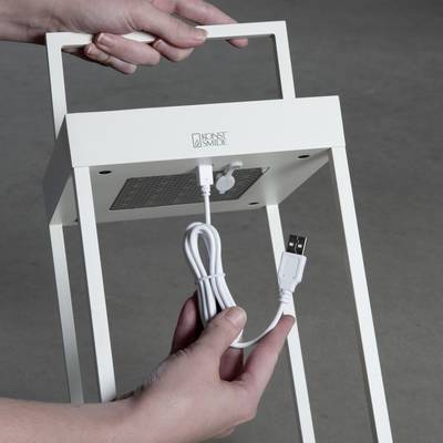 Zwei Hände stecken ein USB-Kabel in einen weißen LED-Beleuchtungsständer.