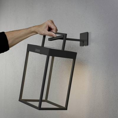 Eine Hand hält eine moderne, rechteckige Außenwandlampe an einer Wand, die in einem minimalistischen Stil gestaltet ist.