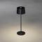 Eine einzelne, moderne schwarze Stehlampe wirft warmes Licht auf den grauen Boden darunter.