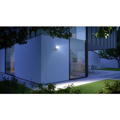 Ein modernes Haus bei Nacht mit eingeschaltetem Außenlicht. Große Glasfenster geben den Blick auf den beleuchteten Innenraum frei.