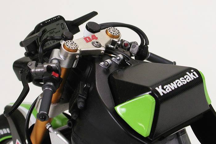 'Nahaufnahme eines Motorrads mit grünen und schwarzen Farben. Es zeigt das Lenkinstrument mit dem 'Kawasaki'-Logo auf der Vorderseite.'