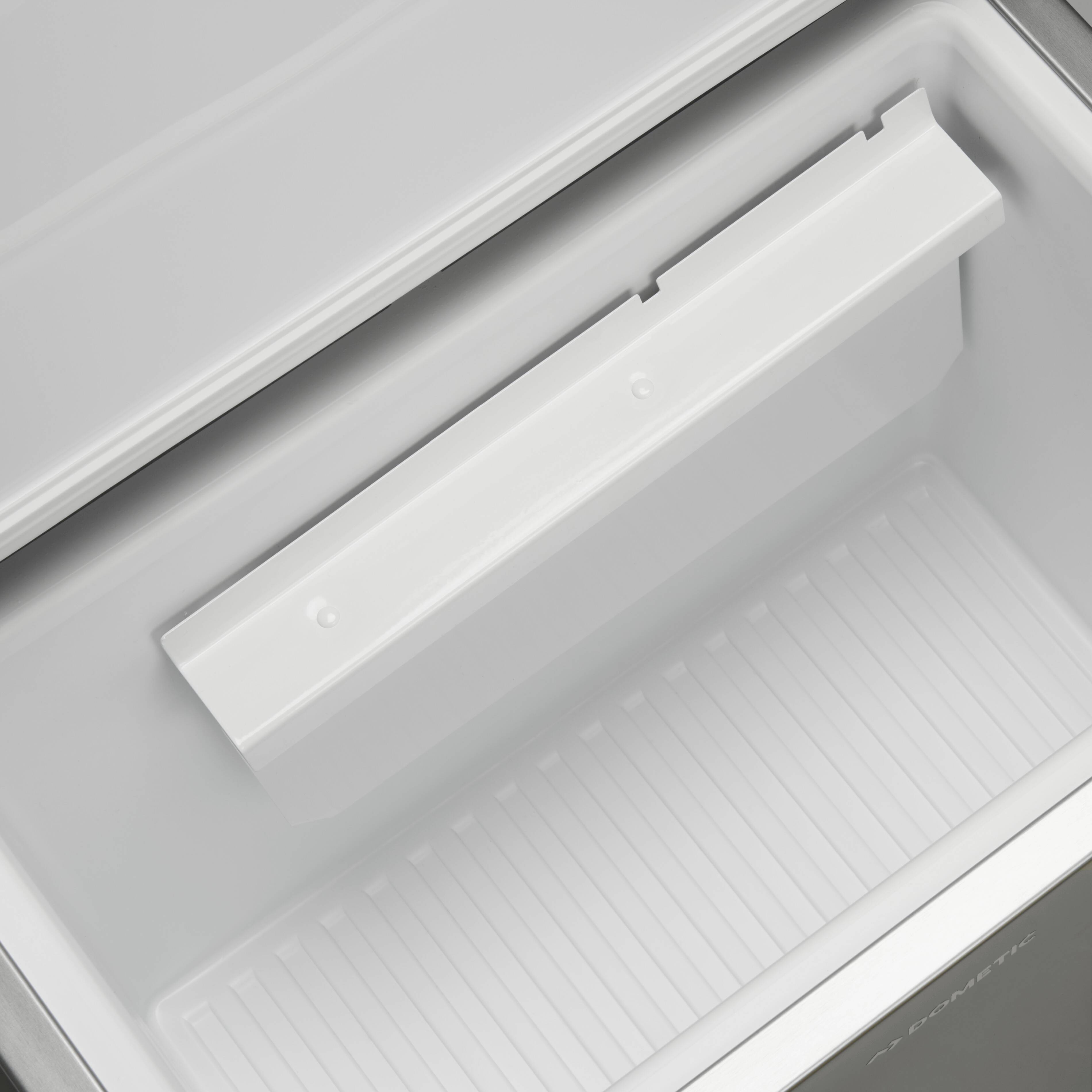 Ein leerer, geöffneter Kühlschrank ohne Inhalt, beleuchtet mit heller Innenbeleuchtung.