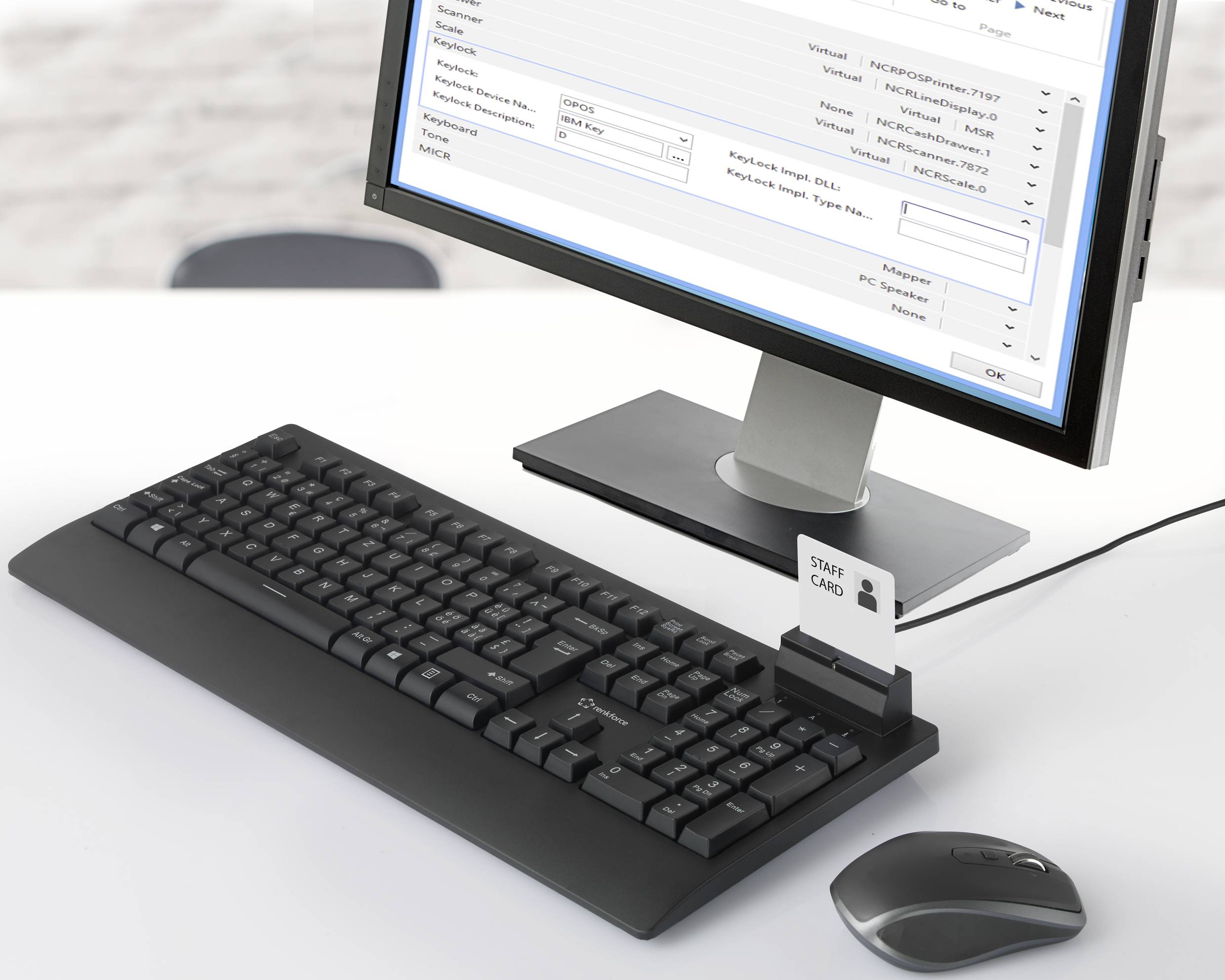 Ein Computer-Arbeitsplatz mit Tastatur, Maus und Monitor. Der Bildschirm zeigt eine Benutzeroberfläche mit Tabellen und Eingabefeldern. Ein Smartcard-Leser ist angeschlossen.