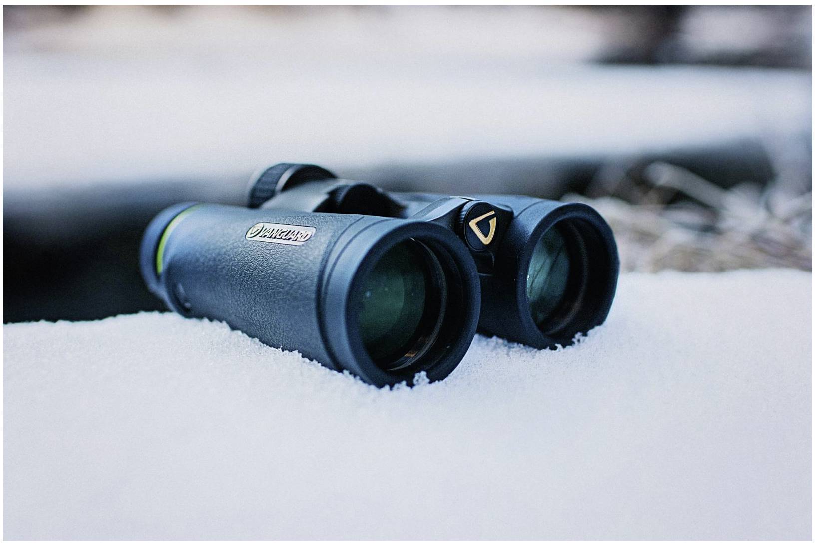 Fernglas, das im Schnee liegt, bereit für die Beobachtung von Natur oder Tieren.