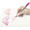 Eine Hand schreibt mit einem pinken Stift kalligrafische Buchstaben auf weißem Papier.