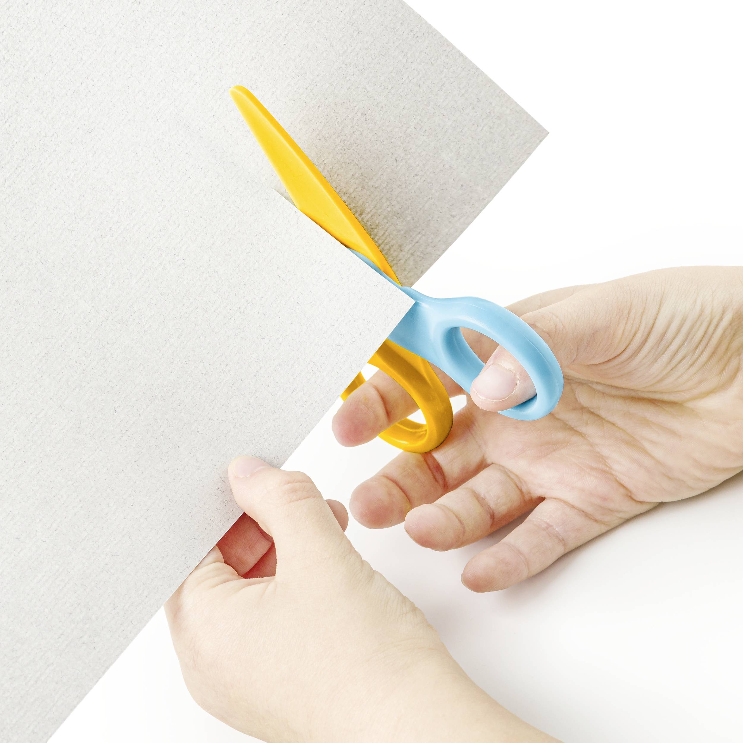 Hände schneiden mit Schere ein Blatt Papier, das teilweise weiß ist.