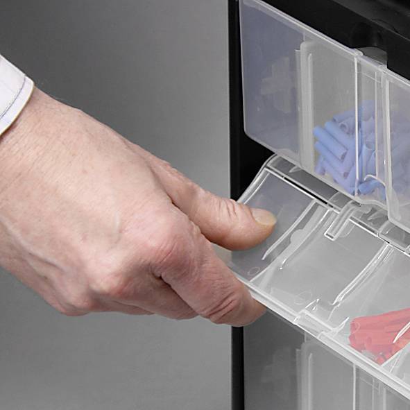 Eine Hand öffnet eine Plastikschublade mit blauen und grauen Kleinteilen.