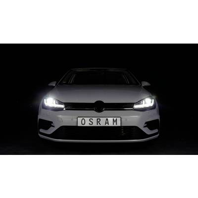 Ein weißes Auto, frontal fotografiert, vor schwarzem Hintergrund. Das Nummernschild zeigt 'OSRAM'. Die Frontlichter sind eingeschaltet.