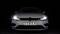 Ein weißes Auto, frontal fotografiert, vor schwarzem Hintergrund. Das Nummernschild zeigt 'OSRAM'. Die Frontlichter sind eingeschaltet.