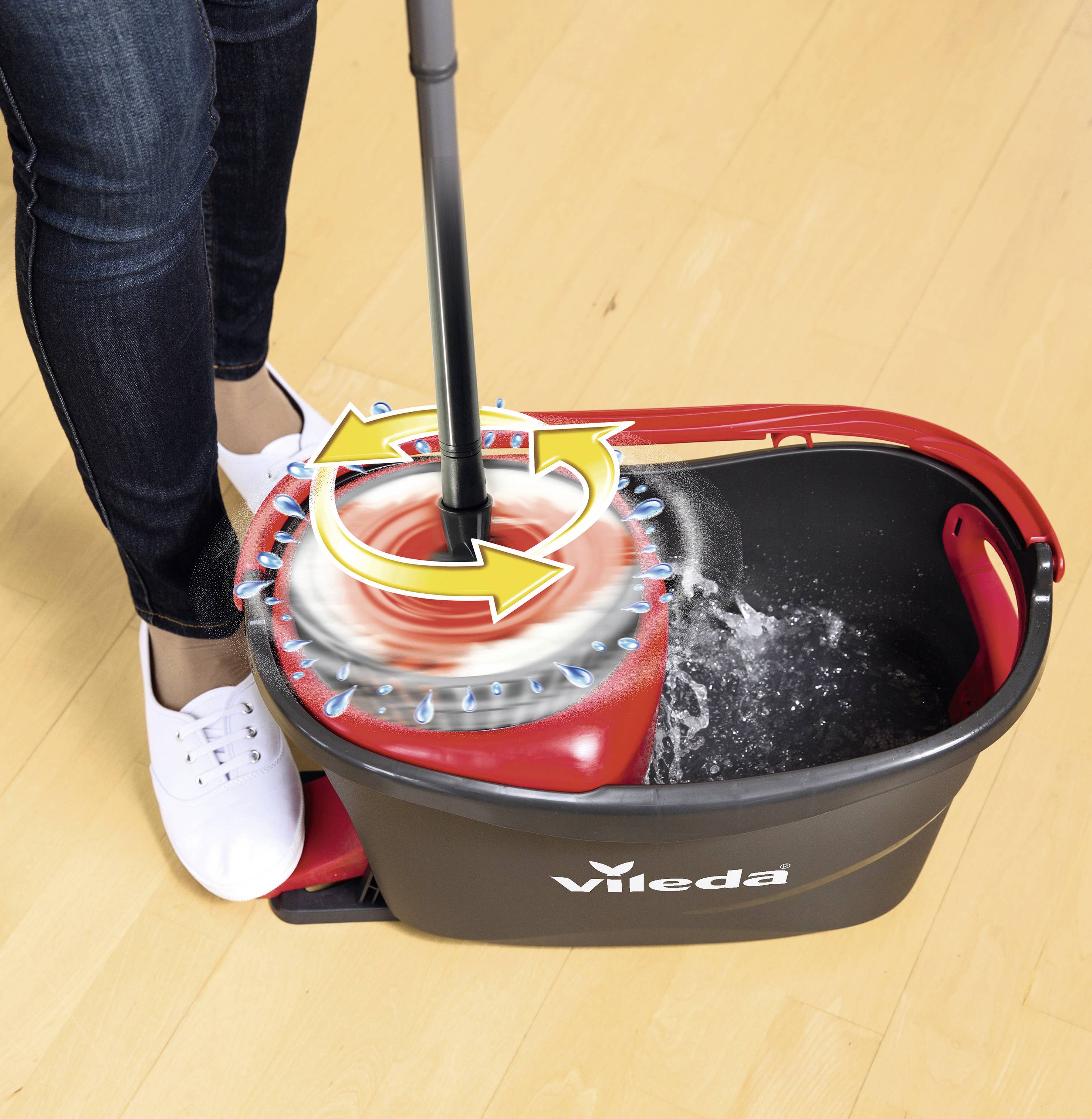 Person reinigt Mop mit Vileda-Spin-Mop-Eimer, der Wasser durch Drehmechanismus entfernt. Eimer steht auf hellem Holzboden.