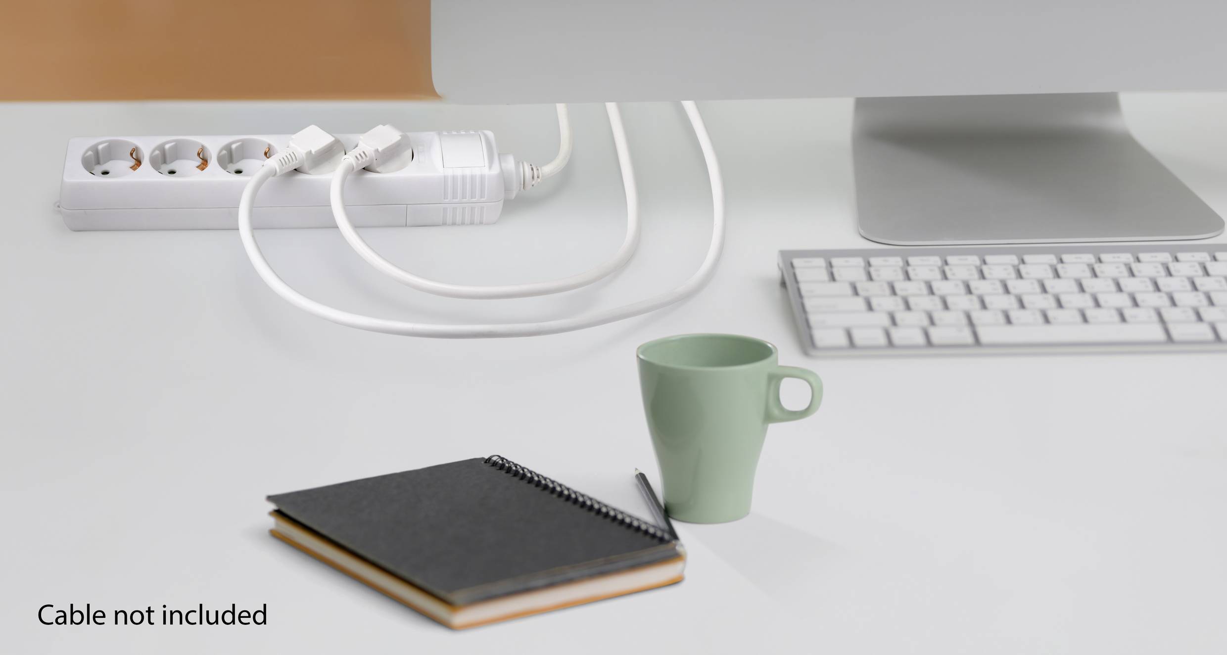 Ein weißer Schreibtisch mit einem Computer, einer Tastatur, einer grünen Tasse, einem Notizbuch und einem Stift. Kabel fehlen.