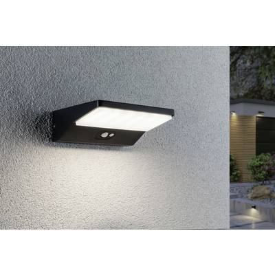 Beleuchtete Wandleuchte mit integriertem Bewegungssensor an einer Hauswand, sorgt für Außenbeleuchtung in einem modernen Gartenbereich.