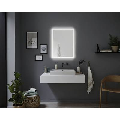Moderner Badezimmerbereich mit beleuchtetem Spiegel, weißem Waschbecken auf Wandkonsole, Pflanzen und Dekoration an dunkler Wand.