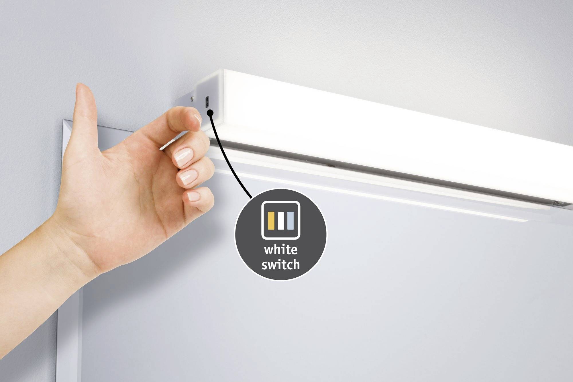 Eine Hand schaltet eine weiße Leuchte mit einem seitlichen Schalter ein. Ein Symbol daneben zeigt 'white switch'.