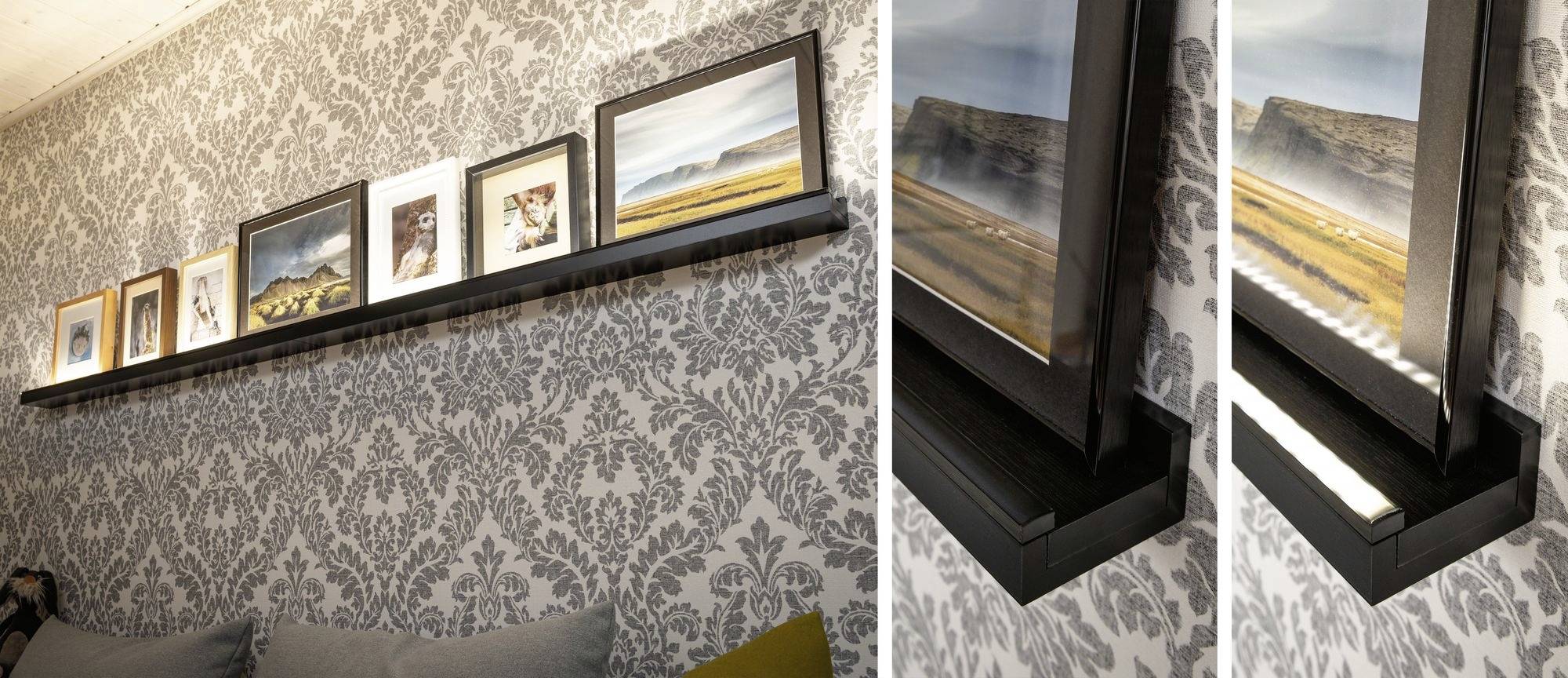 Eine wandmontierte Bilderleiste im Wohnzimmer zeigt sieben gerahmte Bilder vor einer grau-weißen Tapete mit floralen Mustern.