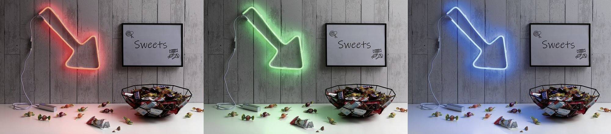 Neonschrift-Schilder in Rot, Grün und Blau zeigen auf eine Schüssel mit Süßigkeiten, Wand mit 'Sweets' Text im Hintergrund.