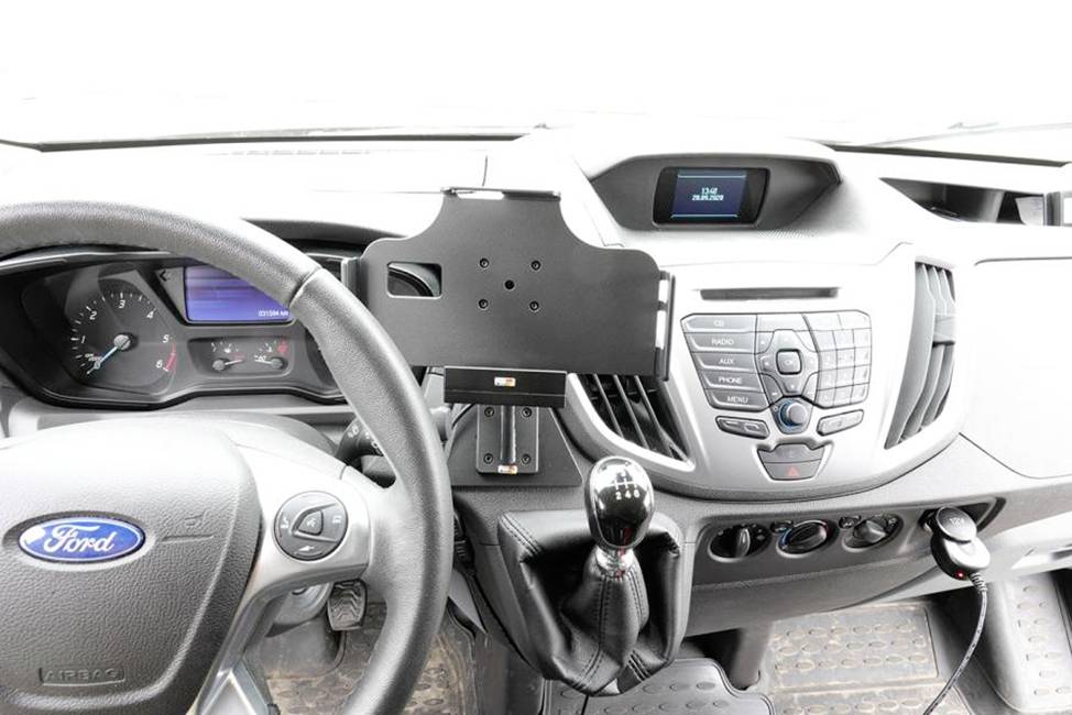 'Innenraum eines Autos mit Lenkrad, Schalthebel und Display. Mittelkonsole mit Belüftungsschlitzen und Radio. Handyhalterung montiert.'