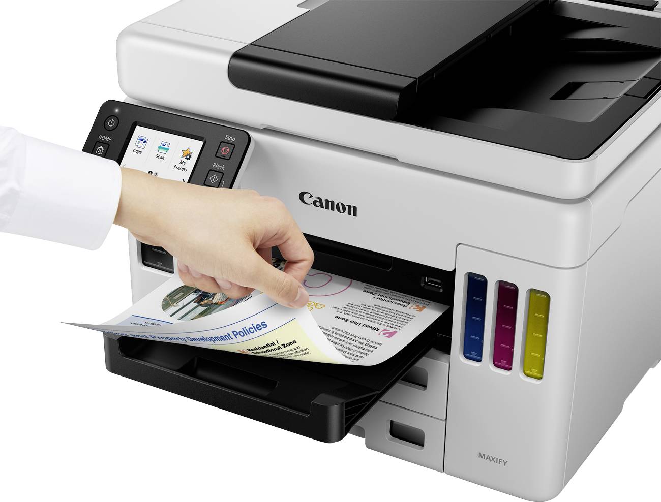 Ein Drucker mit Dokumentenausgabe. Eine Hand entnimmt ein bedrucktes Blatt mit buntem Diagramm. Gerät mit LCD-Display und Farbpatronen sichtbar.