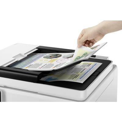 Eine Hand scannt bunte Dokumente in einem Flachbettscanner. Das Gerät befindet sich in einem modernen Büro.