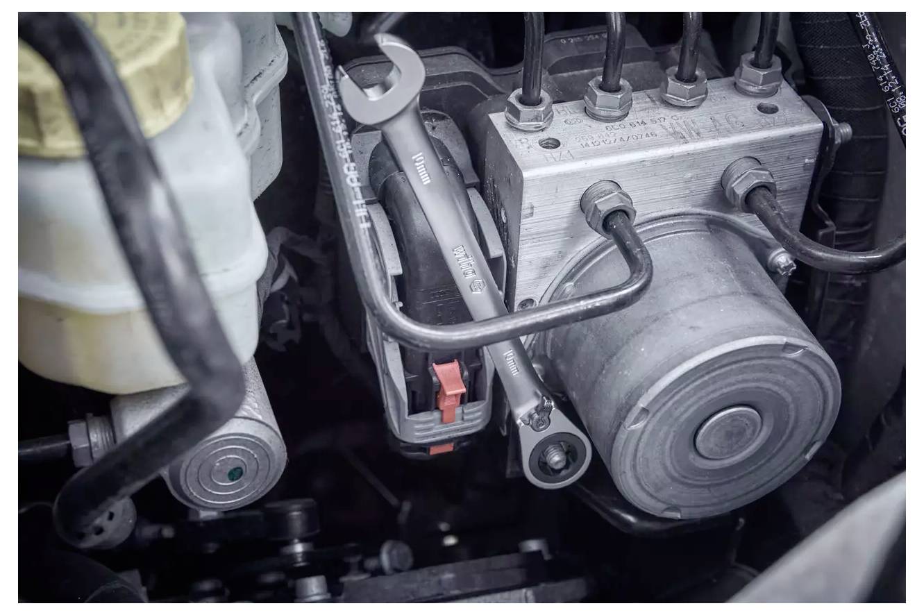 Nahaufnahme einer Motorkomponente mit sichtbaren Rohren, Schläuchen und Metallteilen, die einen Aspekt der Motormechanik und des Designs zeigt.