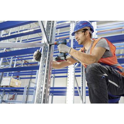 Arbeiter mit Schutzhelm und Weste montiert mit Akku-Schrauber ein Metallregal in einem Lager, symbolisiert Effizienz und Sicherheit.