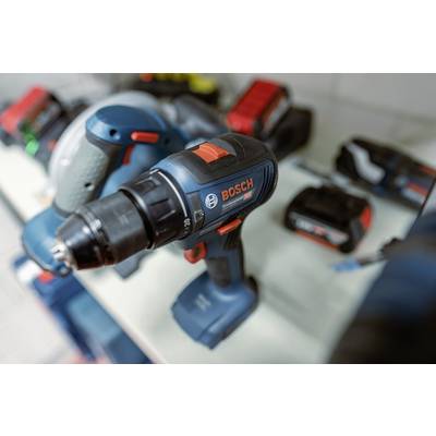 Akkubohrmaschine und Zubehör auf einem Tisch. Im Hintergrund weitere Werkzeuge unscharf. Hauptfarbe Blau mit roten Akzenten.