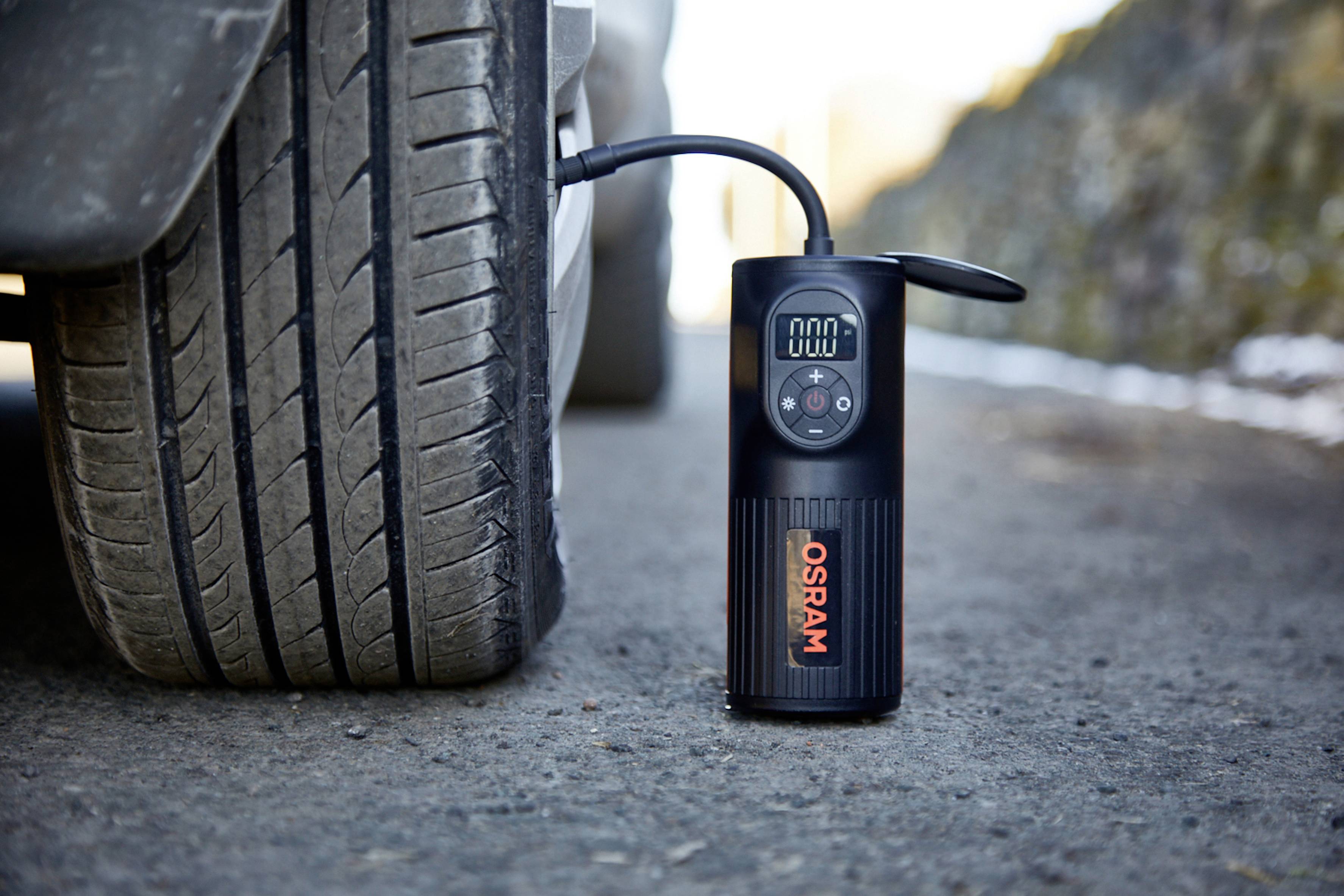 Tragbarer Reifenkompressor pumpt Autoreifen am Straßenrand auf.