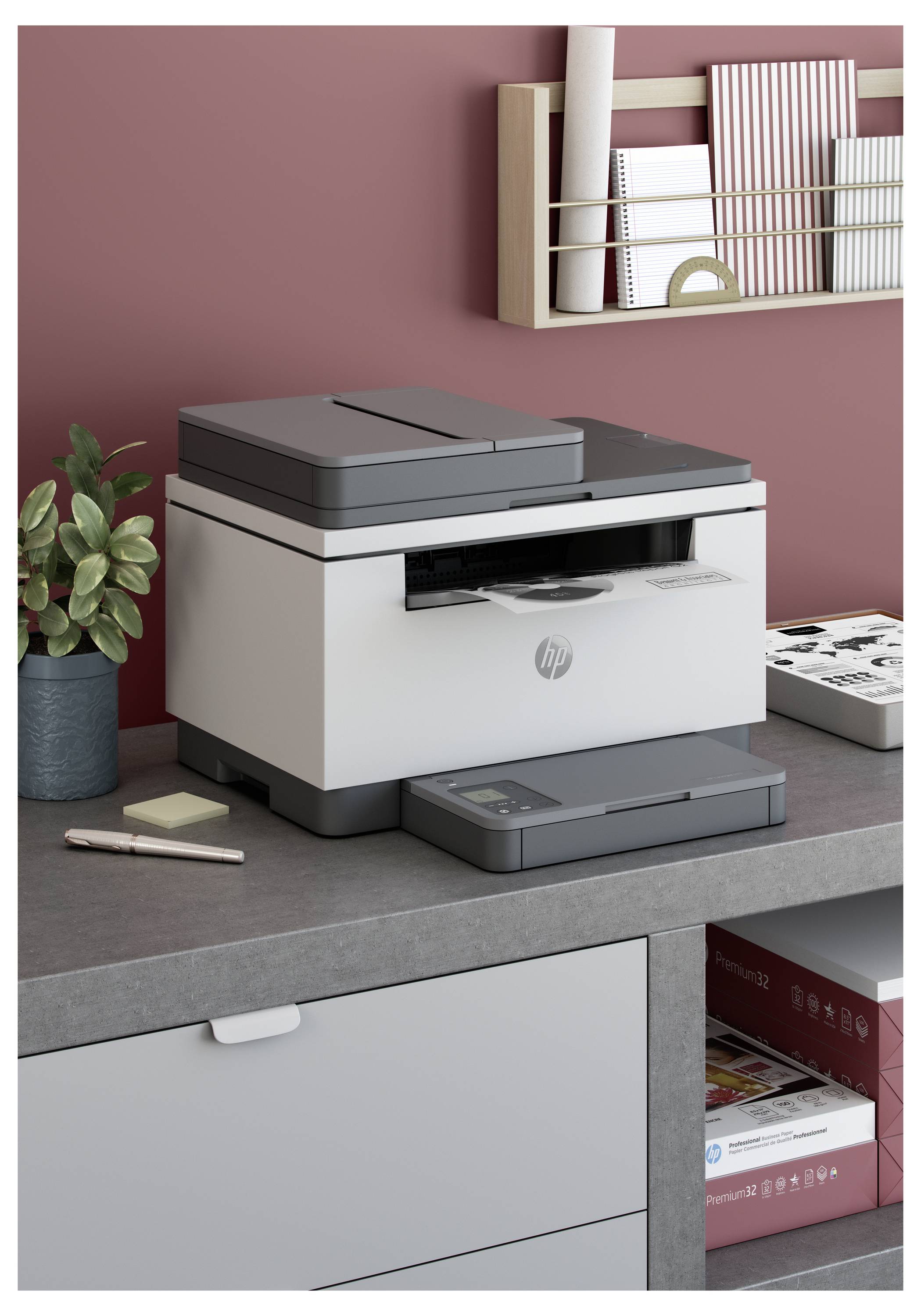 HP Multifunktionsdrucker auf einem Schreibtisch neben einer Topfpflanze und Schreibwaren, mit Regalen und Bürobedarf im Hintergrund.