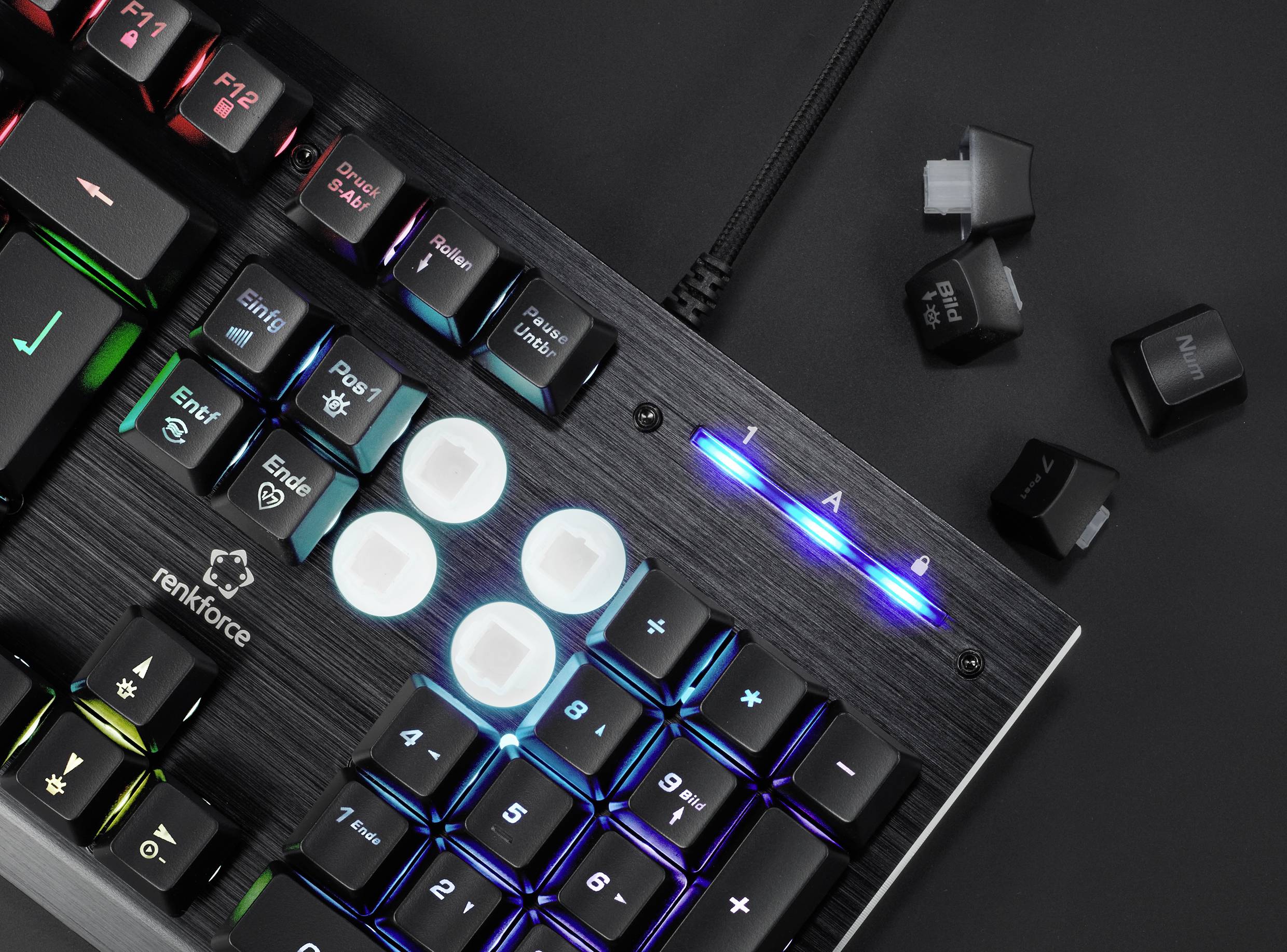 Gaming-Tastatur mit beleuchteten Tasten und blauen LED-Streifen. Einige Tasten wurden entfernt und liegen daneben.