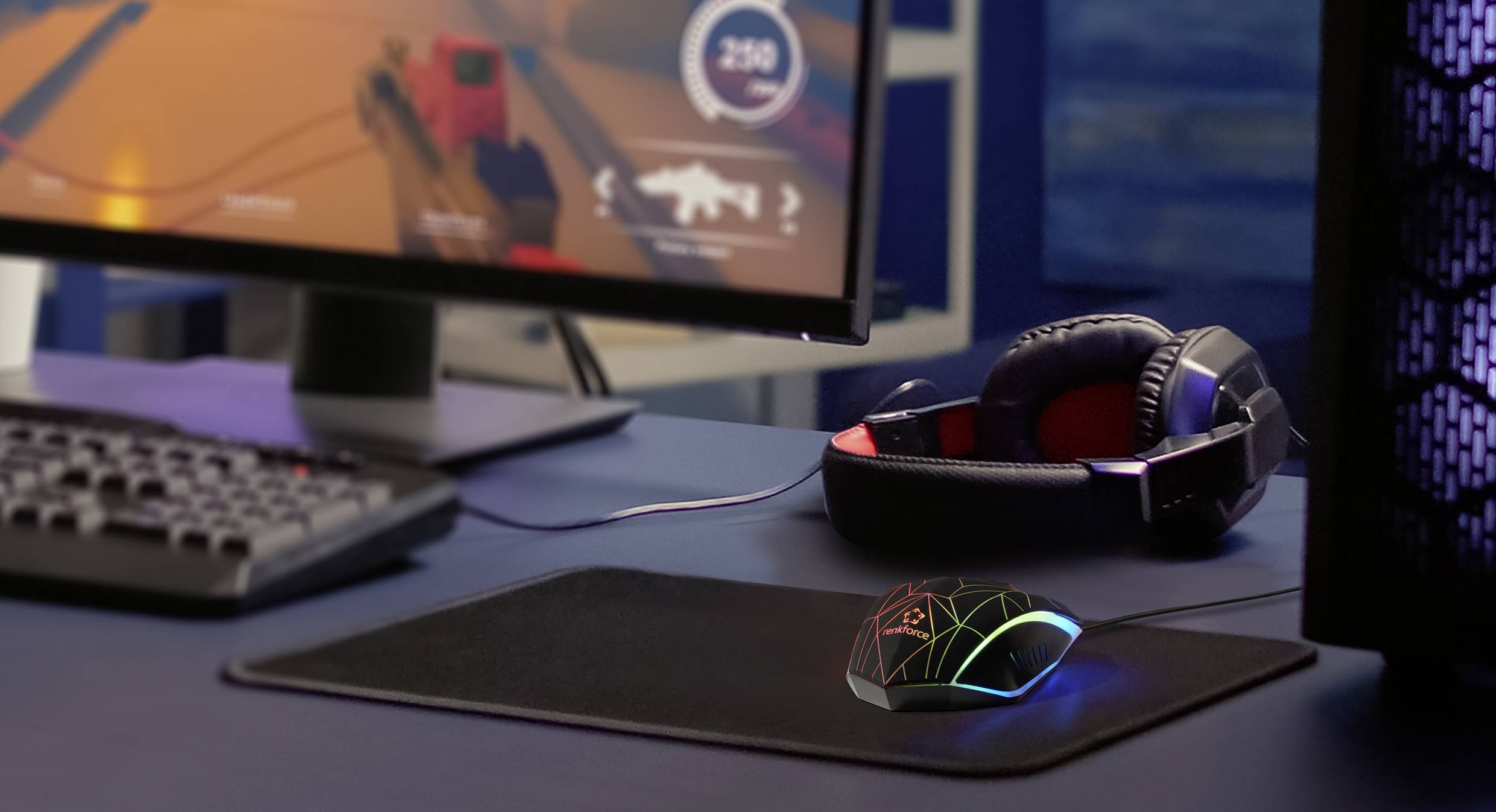 'Gaming-Setup mit Monitor, Kopfhörer und beleuchteter Maus auf Tisch. Spielszene auf dem Bildschirm zeigt Action-Shooter.'