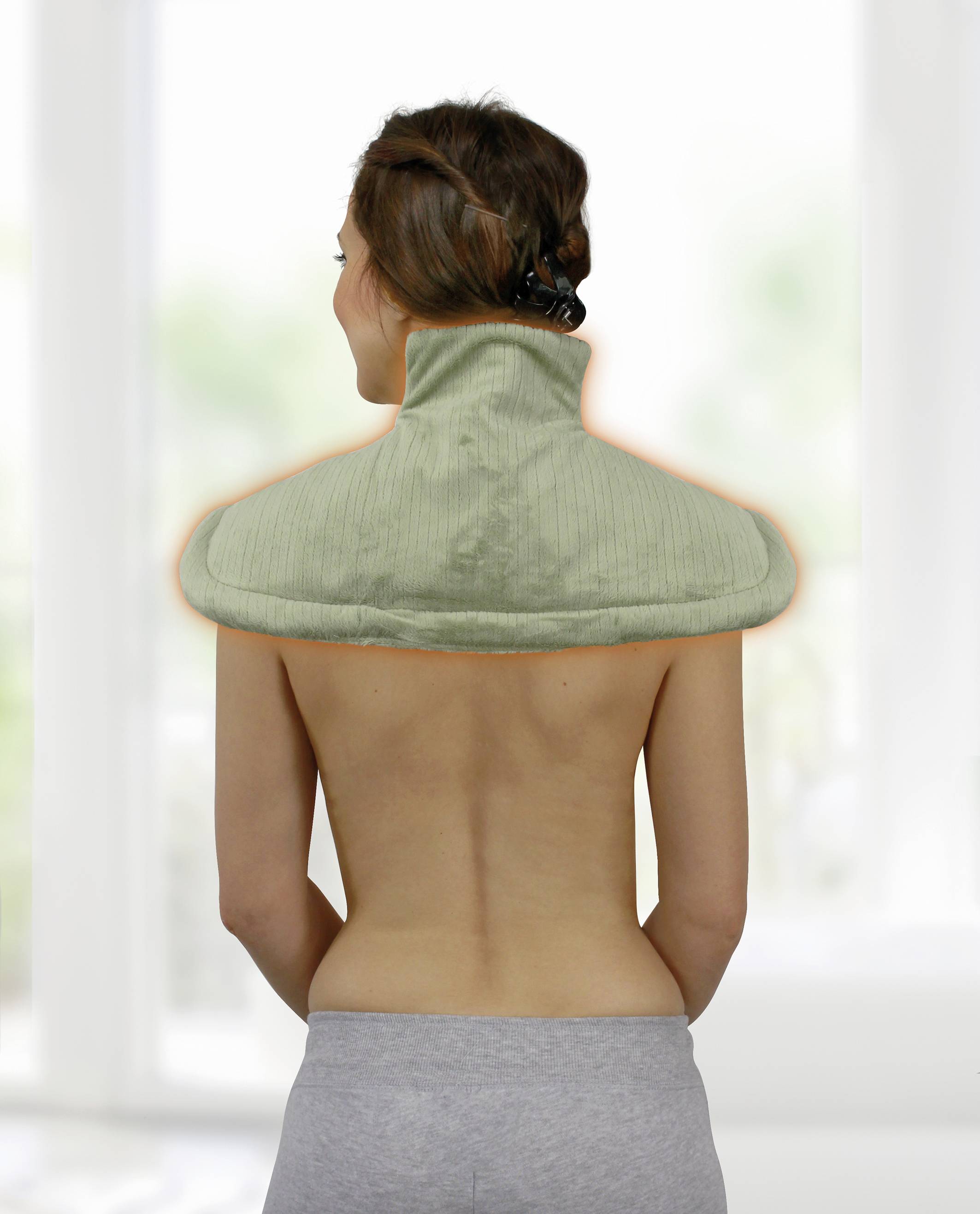 Eine Frau von hinten mit freiem Rücken trägt ein Nacken- und Schultermassagekissen. Der Raum ist hell erleuchtet.