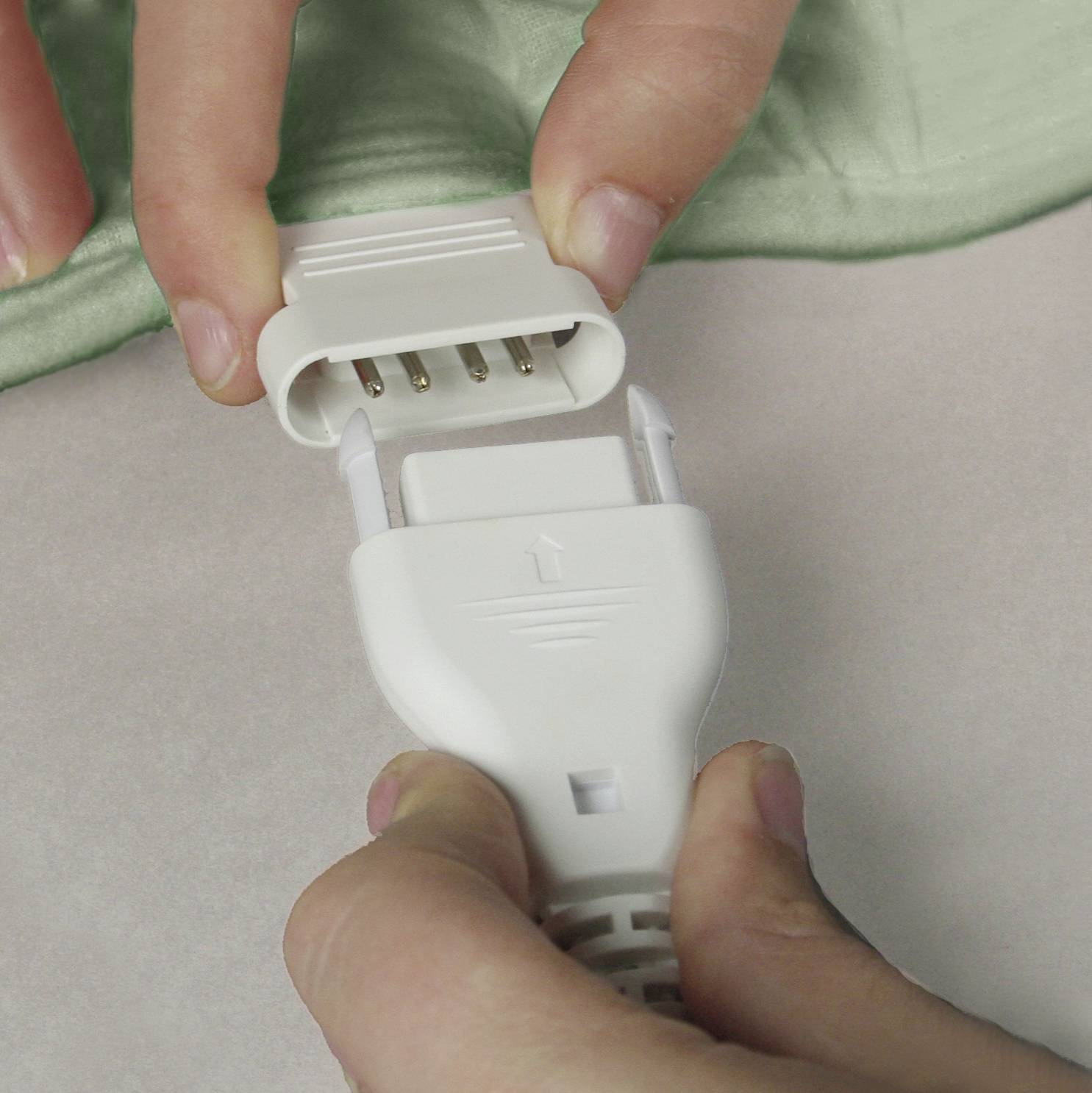 'Nahaufnahme von Händen, die einen weißen Stecker in eine passende Buchse einstecken. Beide Verbinder sind rechteckig mit Metallkontakten.'