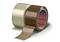Zwei Rollen Klebeband, eine durchsichtig, eine braun, aufrecht stehend. Die braune Rolle hat ein sichtbares 'tesa' Logo auf der Innenseite.