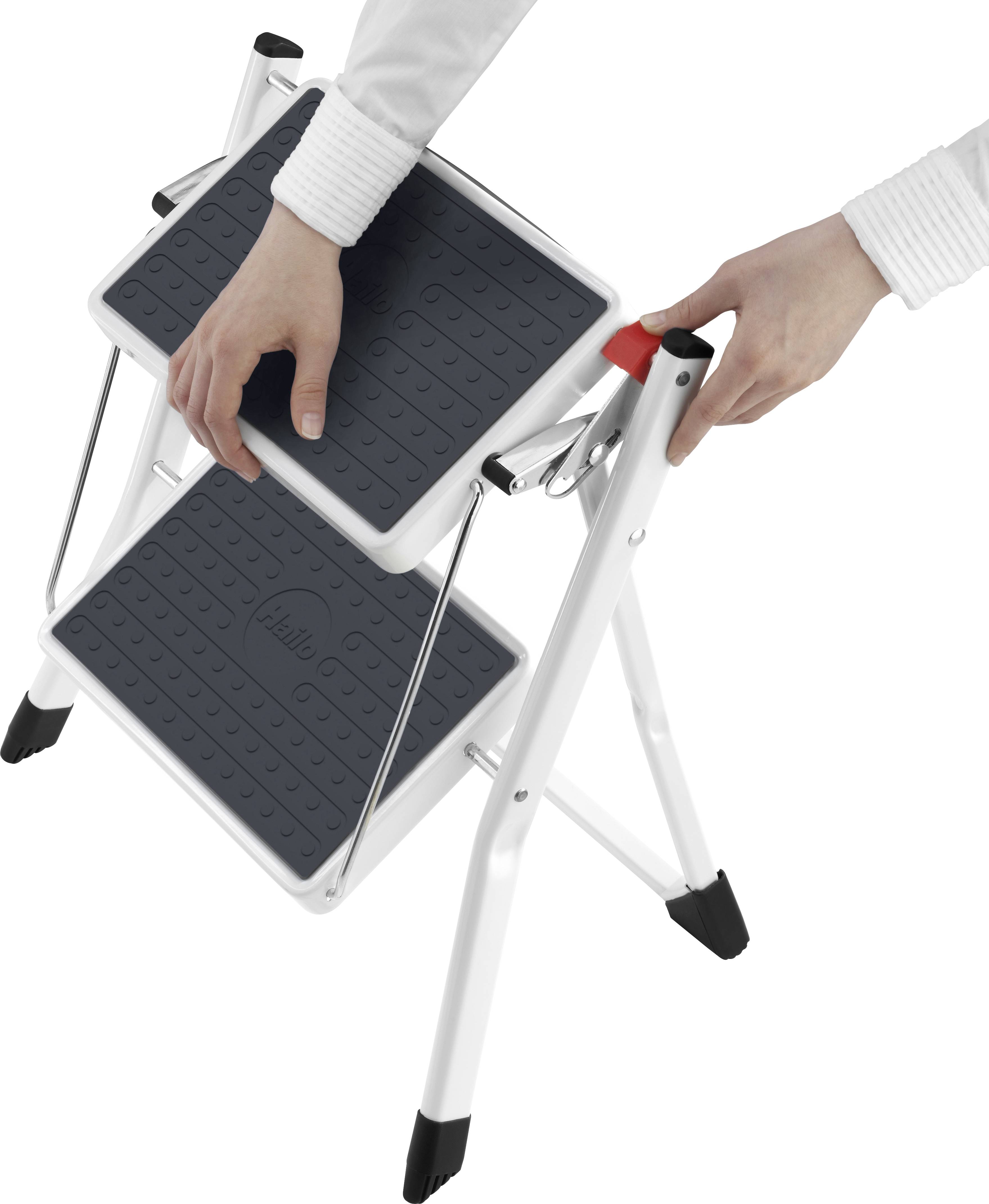 Eine Person faltet einen weißen Klapptritt mit zwei schwarzen Stufen zusammen.