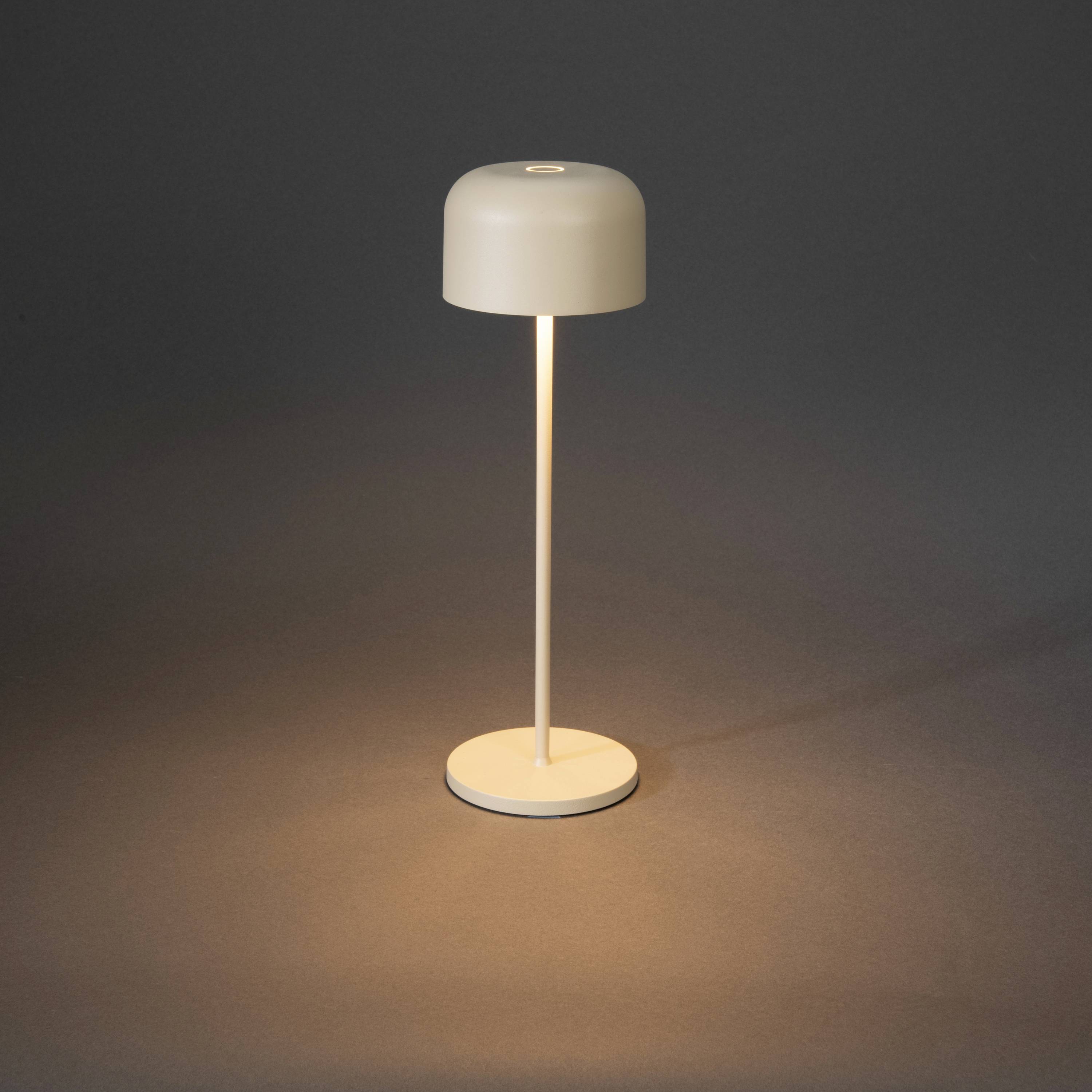 Eine minimalistische Tischlampe mit rundem, weißem Schirm und schmalem Standfuß strahlt warmes Licht auf eine dunkle Oberfläche.