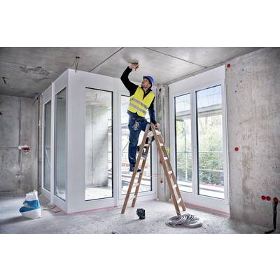 Ein Bauarbeiter auf einer Leiter in einem Rohbau streicht die Decke. Er trägt einen gelben Sicherheitshelm und eine Warnweste.