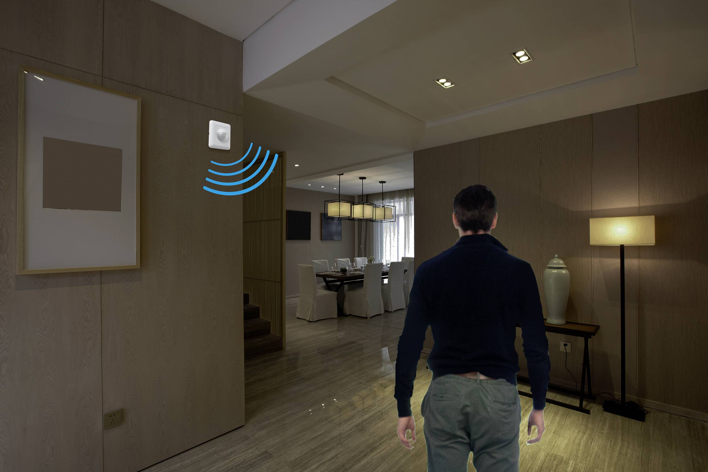 Eine Person betritt einen modern eingerichteten Raum. Ein Sensor an der Wand aktiviert eine Lampe, die den Raum beleuchtet.