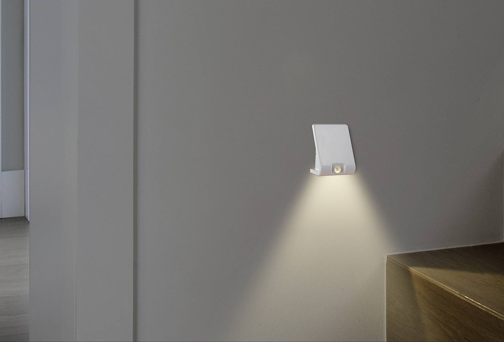 Eine moderne, an der Wand montierte Nachtleuchte beleuchtet dezent eine Treppe, schafft eine sichere und angenehme Atmosphäre.