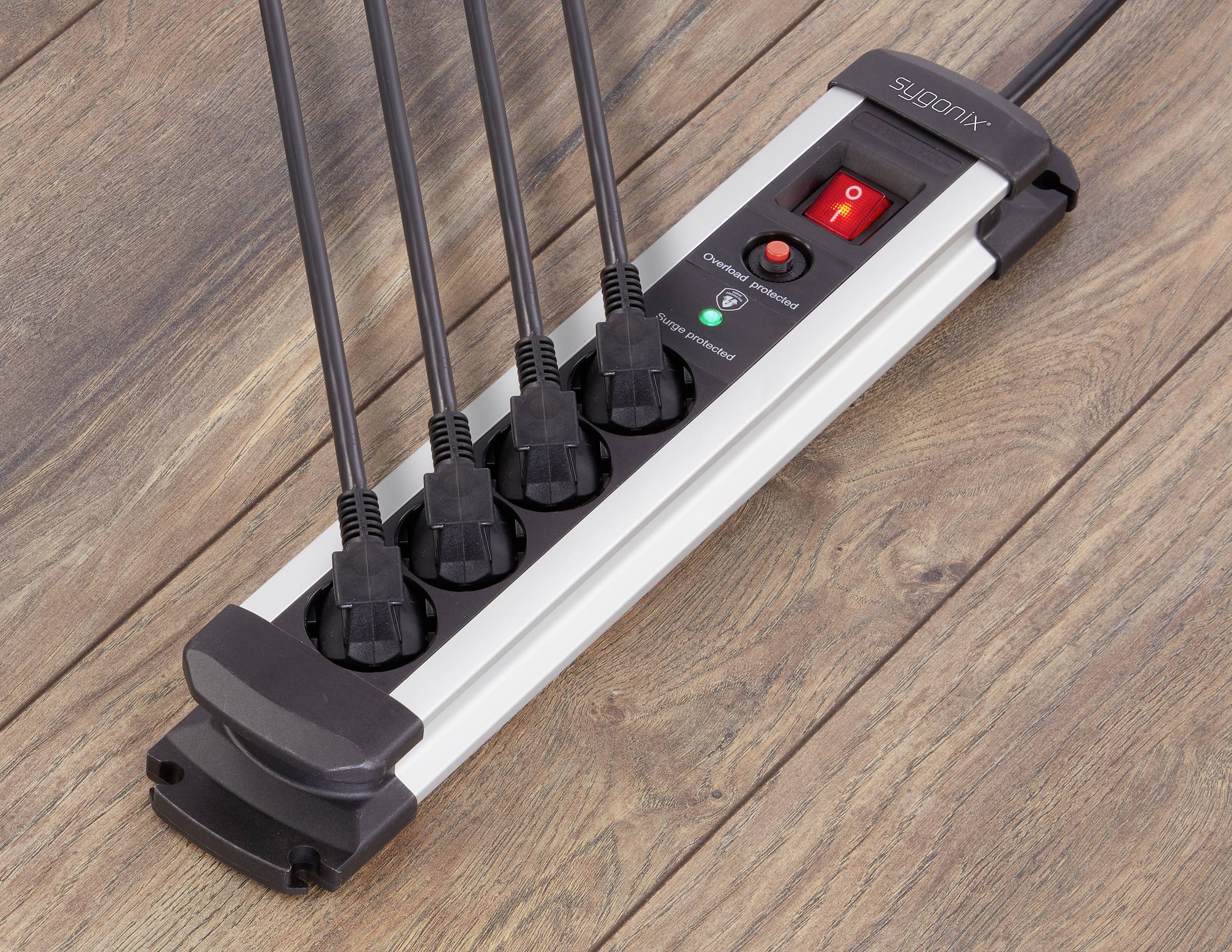 Mehrfachsteckdose mit fünf eingesteckten Kabeln auf Holzoberfläche. Schalter und Kontrolllicht sichtbar.
