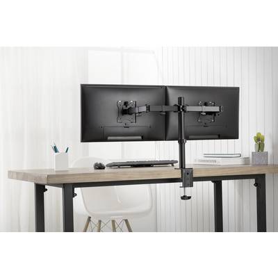 Zwei Monitore auf einem Schreibtisch mit Dual-Monitor-Halterung; im Hintergrund Fenster, daneben Stuhl und Dekorationen.