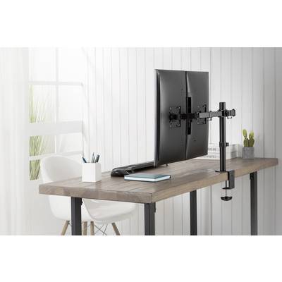 Ein Schreibtisch mit einem doppelt montierten Monitorarm, zwei Monitoren, Laptop, Notizbüchern und Büromaterial in einem hellen Raum.