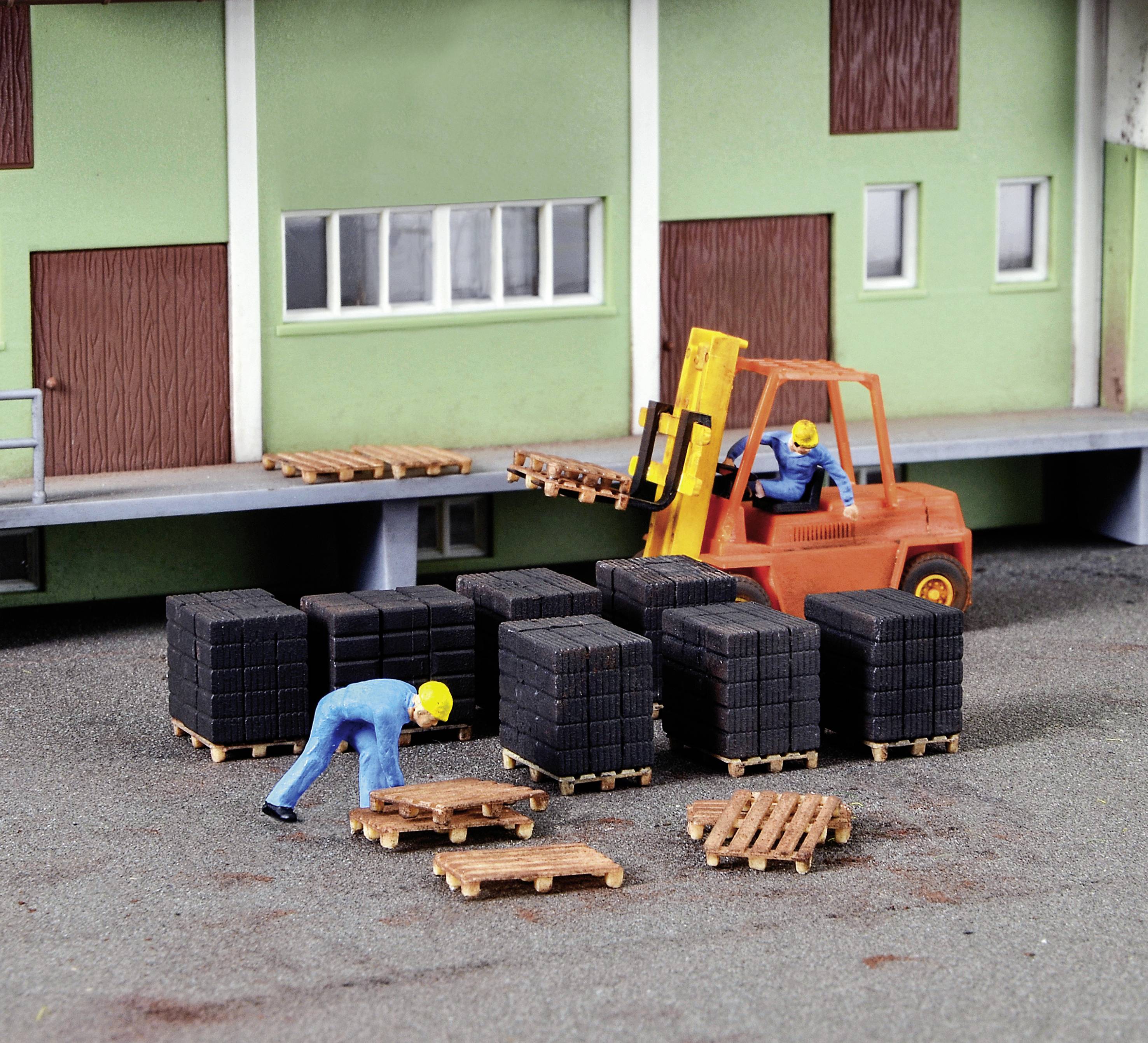 Ein Modell einer Lagerszene mit zwei Figuren, die Paletten stapeln. Ein Gabelstapler hebt eine Holzpalette. Gebäude im Hintergrund.