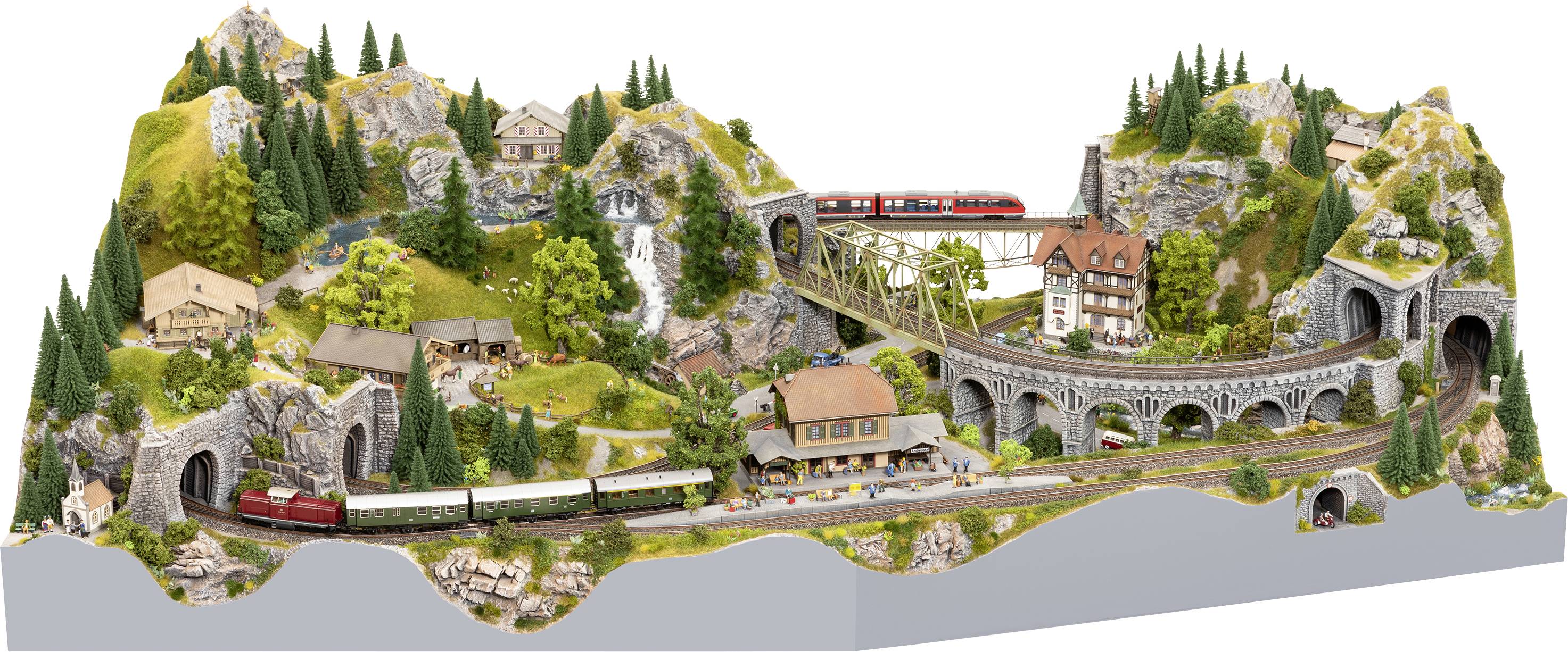 Eine detaillierte Modelleisenbahnlandschaft zeigt Züge, die sich durch Berge, Tunnel und über Brücken bewegen. Umgeben von Bäumen und Gebäuden.