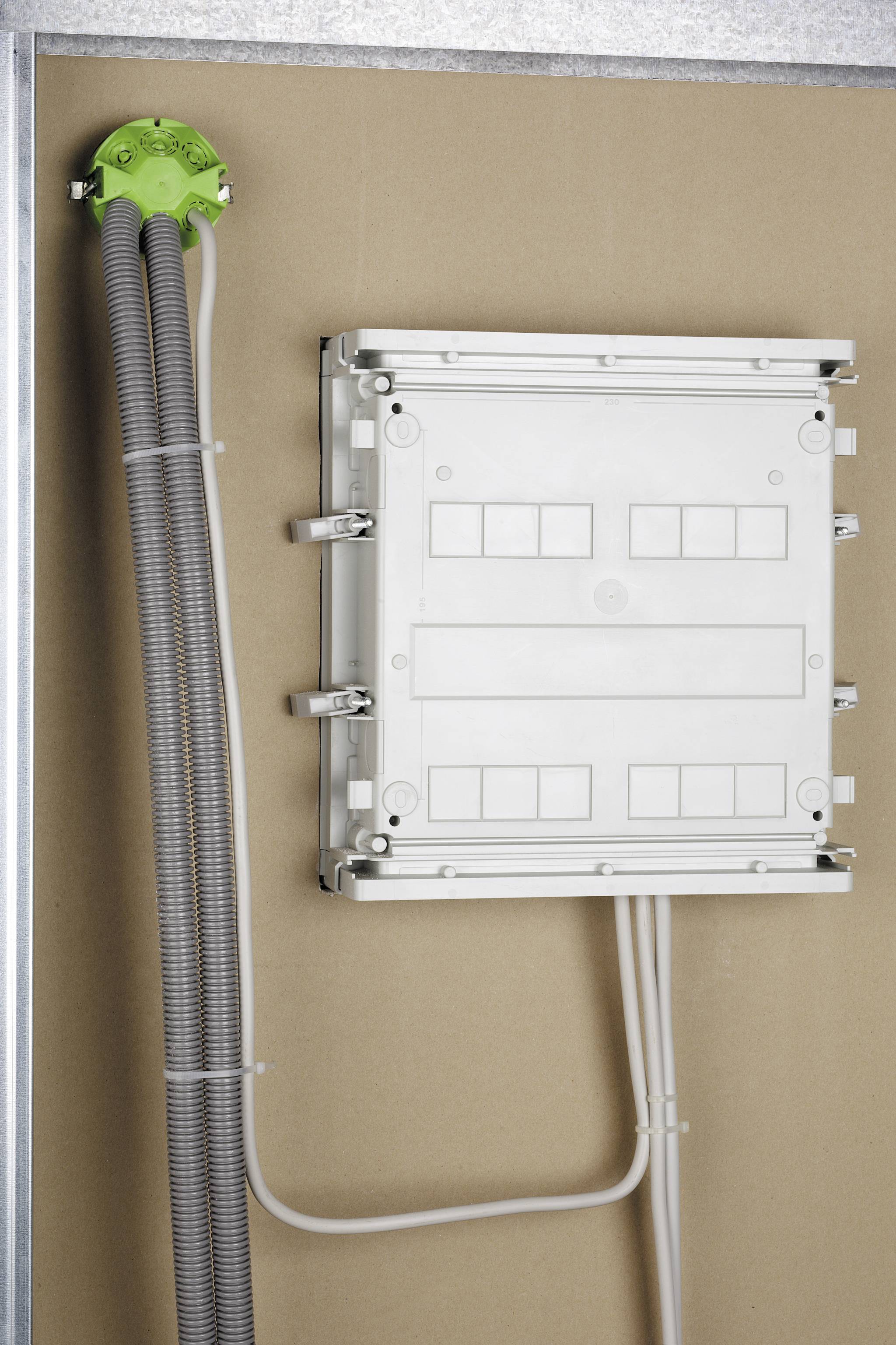 Ein grauer Elektrokasten ist an einer Wand montiert. Kabel führen von der linken Seite in den Kasten, die durch einen grünen Halter gesichert sind.