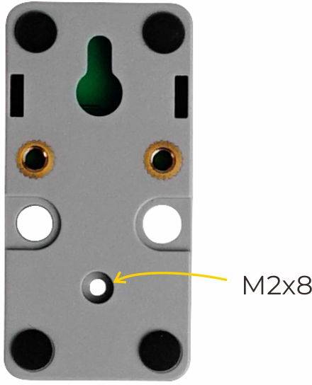 Graues rechteckiges Bauteil mit Bohrungen, zwei Kupfergewinde und Beschriftung 'M2x8' mit Pfeil auf eine mittige Bohrung zeigend.