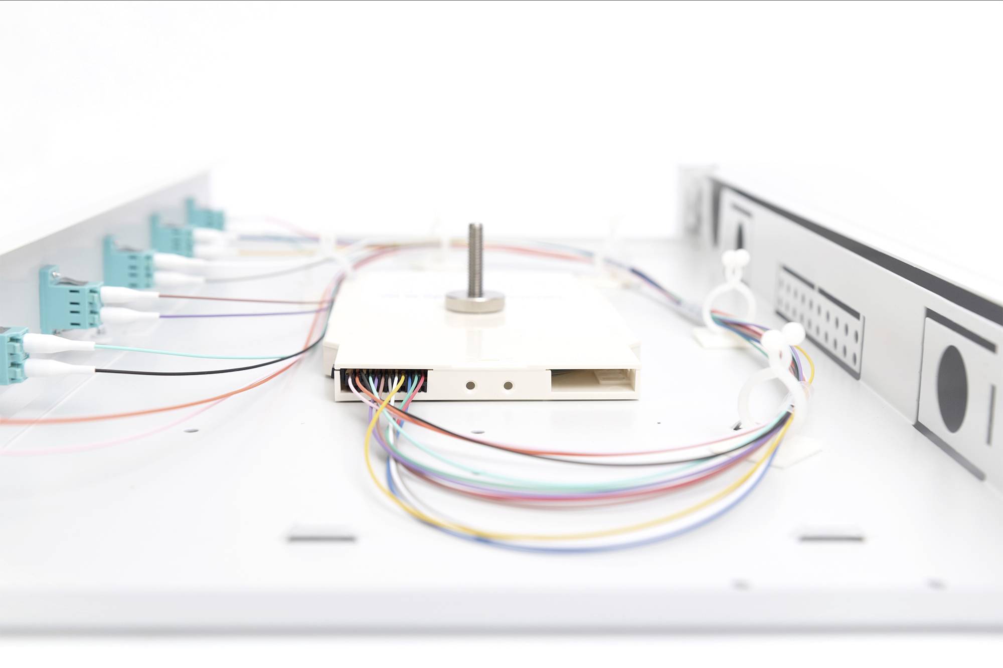 Weiße Schalttafel mit Kabelverbindungen und Steckern, die zentralen Konnektor mit mehreren farbigen Kabeln zeigt.