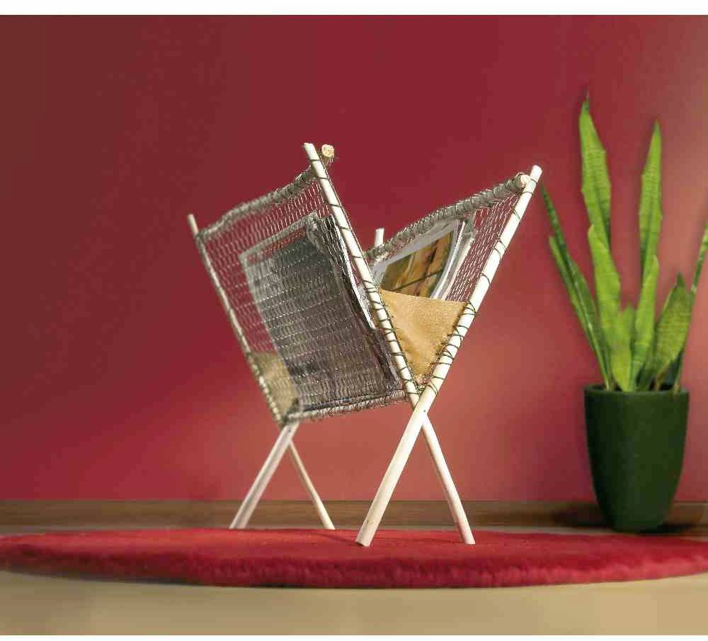 Magazinhalter aus Holz mit Zeitschriften, vor einer roten Wand auf einem roten Teppich. Eine grüne Pflanze in einem schwarzen Topf daneben.