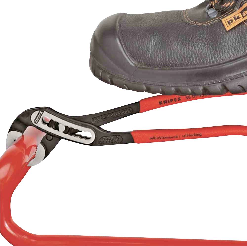 Ein Schraubenschlüssel hält ein rot-schwarzes Kabel, während ein Stiefel darauf steht, um Stabilität oder Druck zu demonstrieren.